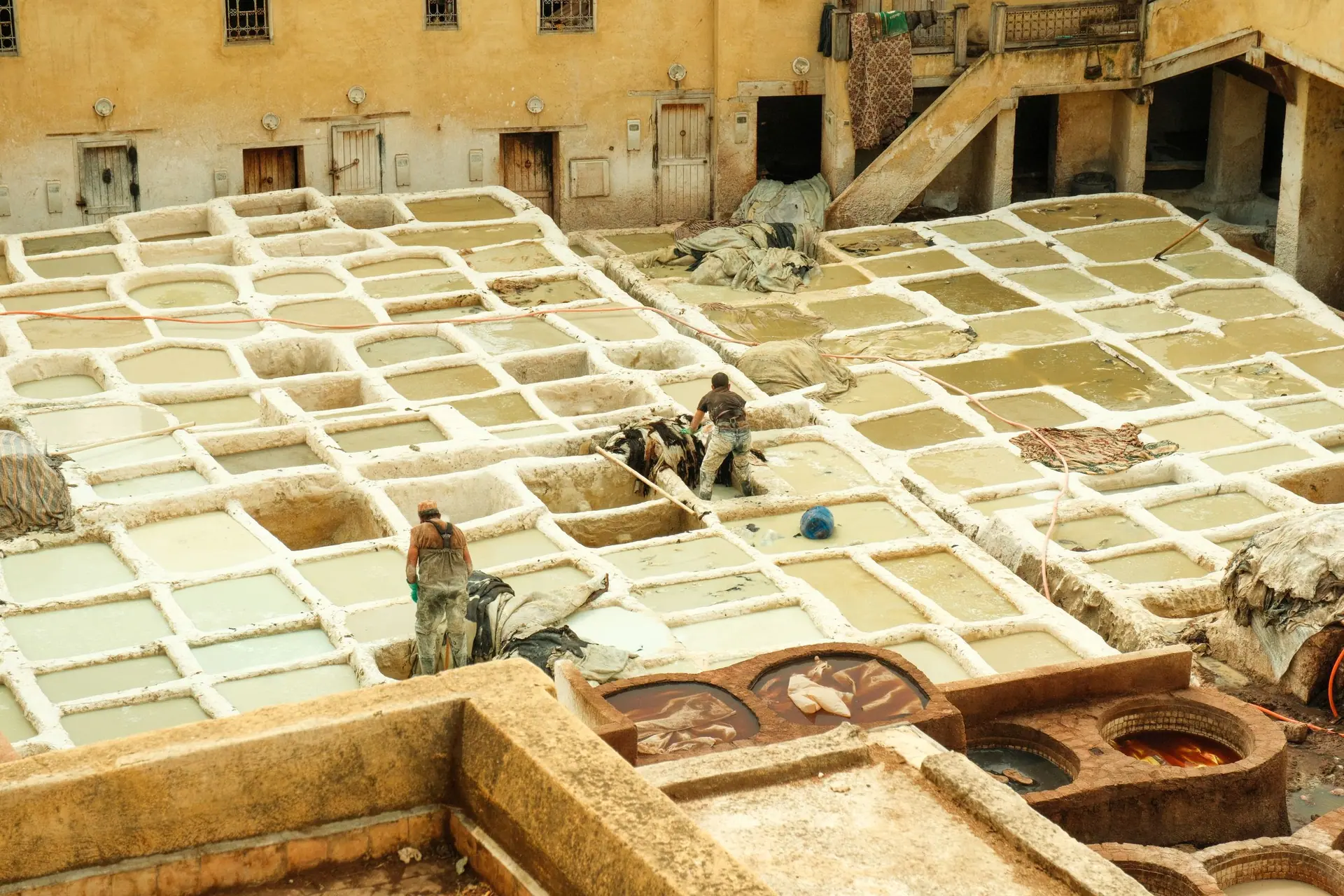 A view of traditional leather tanneries in Fes, Morocco with workers in action.